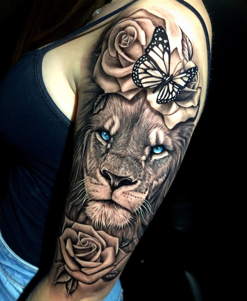 Tatuaż Lew niebieskimi oczami z kwiatami różą, motylkiem na przedramieniu znaczenie dla mężczyzn i kobiet