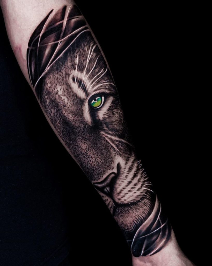 Tatuaż głowa lwa na przedramieniu z kolorowymi oczami