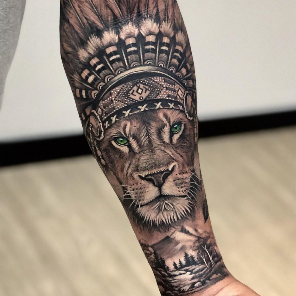 Tatuaż lwa z piórami na głowie z górami, lasem znaczenie dla mężczyzn i kobiet