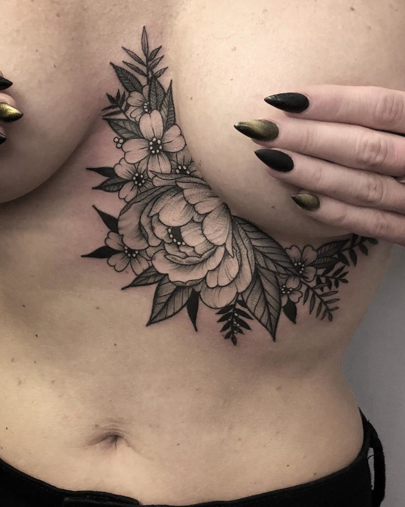Tatuaż pod biustem, piersiami kobiece kwiaty z listkami